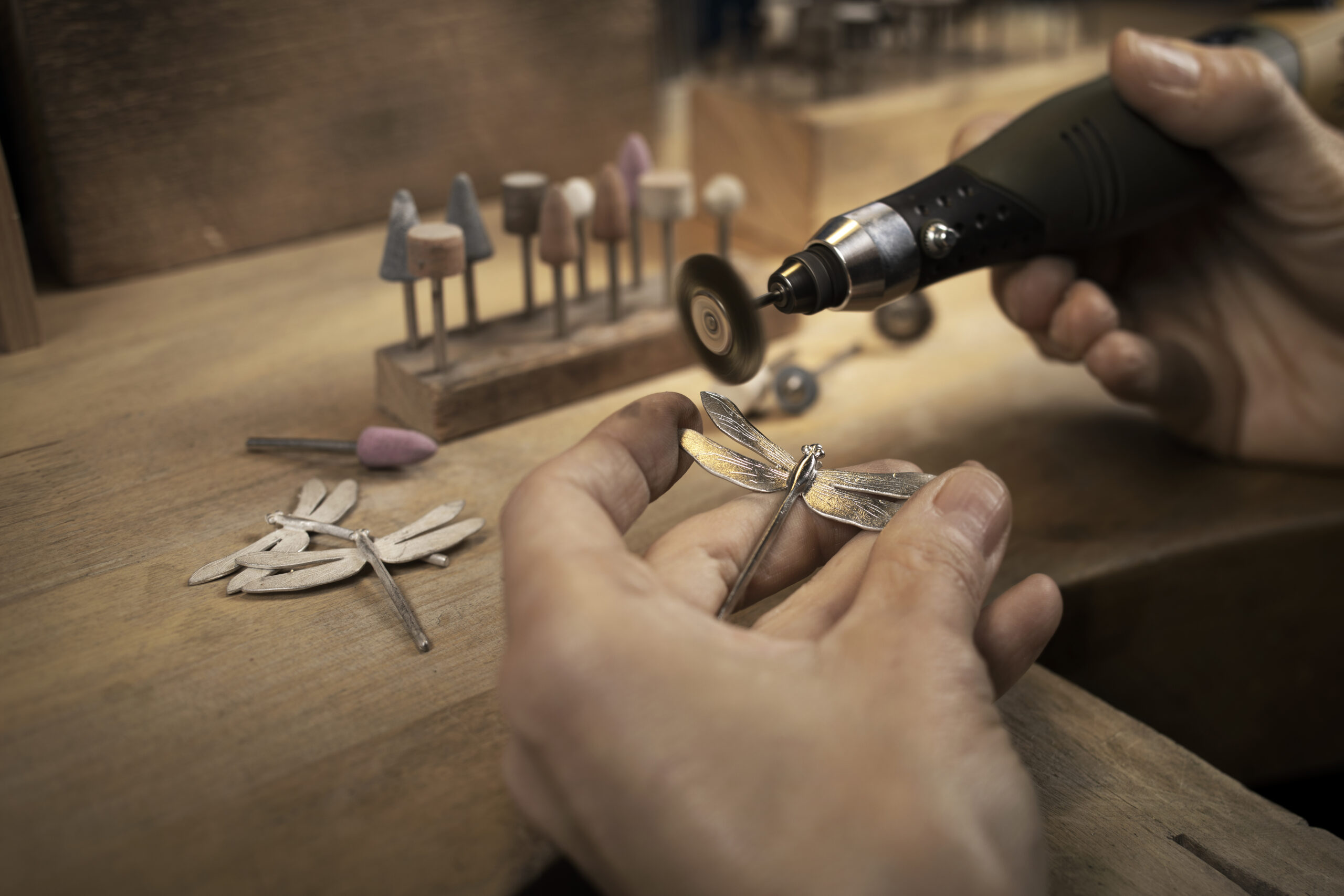Goldsmith polishing a silver jewellery piece with a handheld proxxon micromotor
